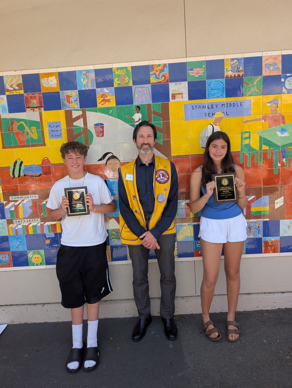 Stanley Middle School students Hudson Bartelt and Ella Roth, with Moraga Lions member Tony Grosso (center).