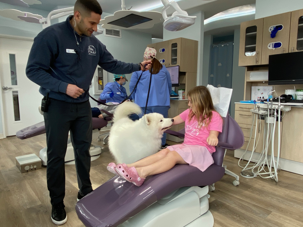 Lexi Diestel, 6, visits with Onyx ahead of her dental checkup as her certified handler, Kaled Forer, looks on. 