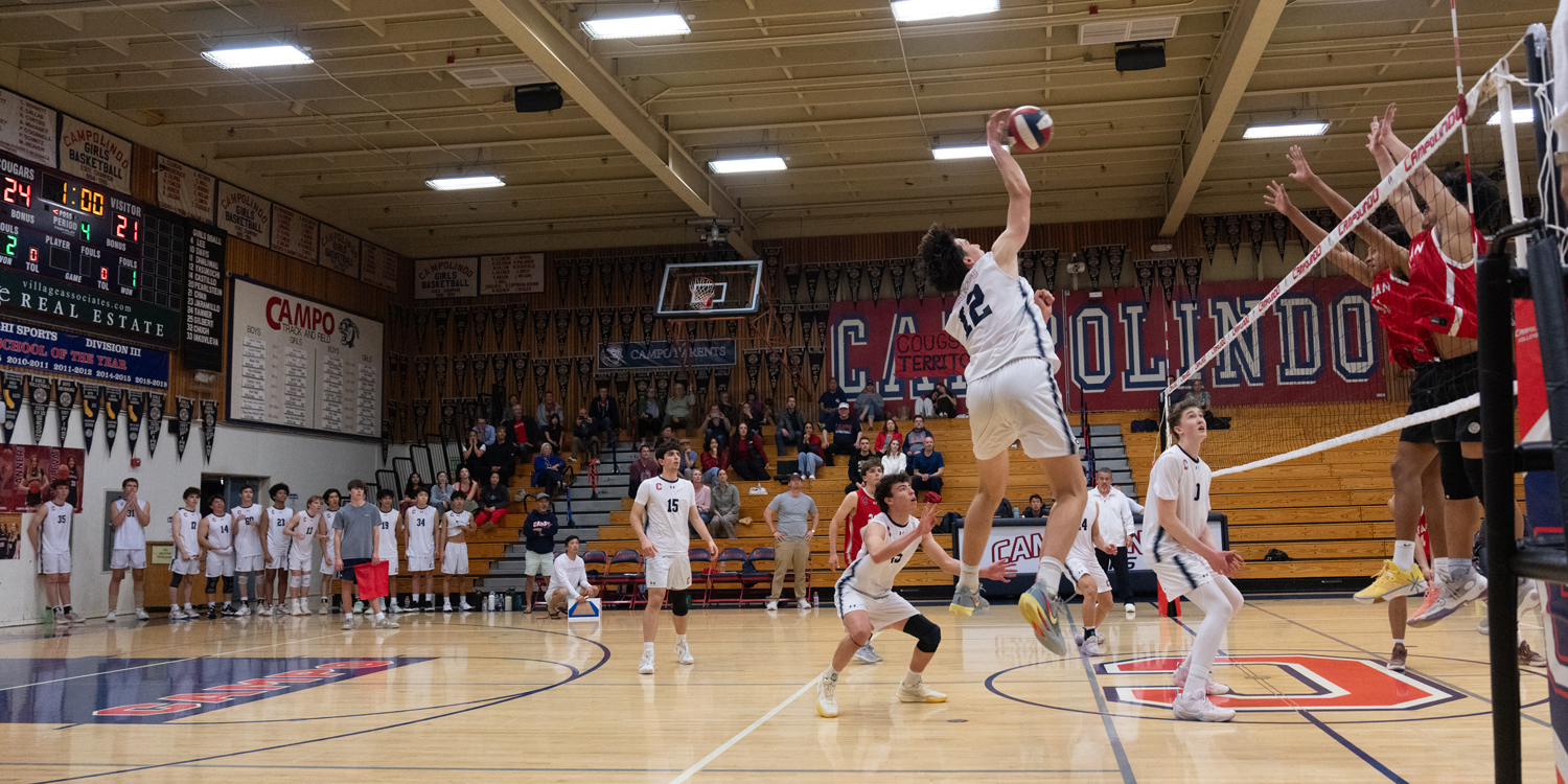 Campolindo outside hitter Claes Bell spikes the ball with #15 Jake Askew and #45 Alex Chng to Bell’s left, and #0 Noah Henry at the net.