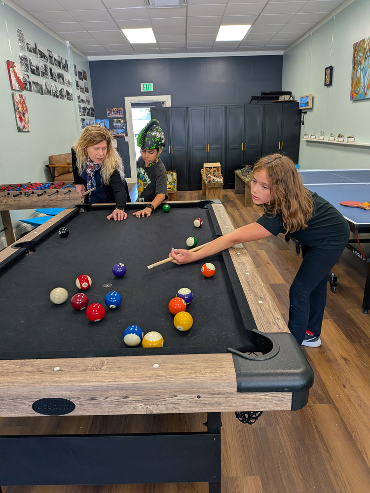 Grace Dixon helps two Lafayette youth sharpen their pool skills.